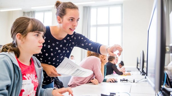 Lehrerin erklärt Schülerin Computerarbeit