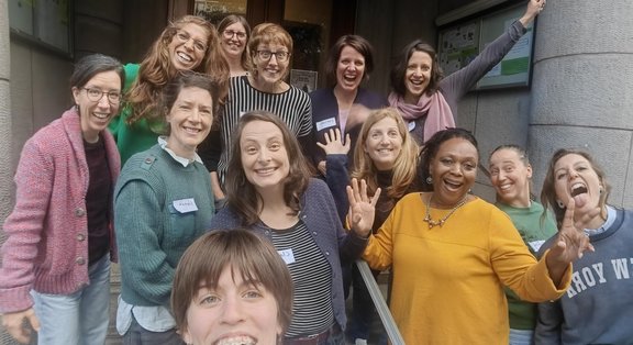 Groupe de femmes joyeuses posant devant un bâtiment